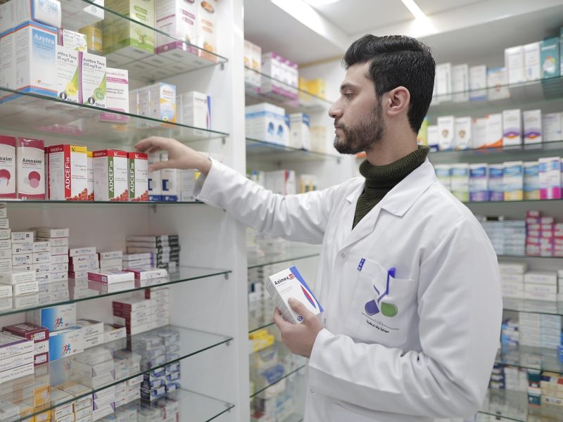 Industrie agro-alimentaire – chimique – pharmaceutique – cosmétique Un pharmacien organise des boîtes de médicaments sur des étagères en verre.